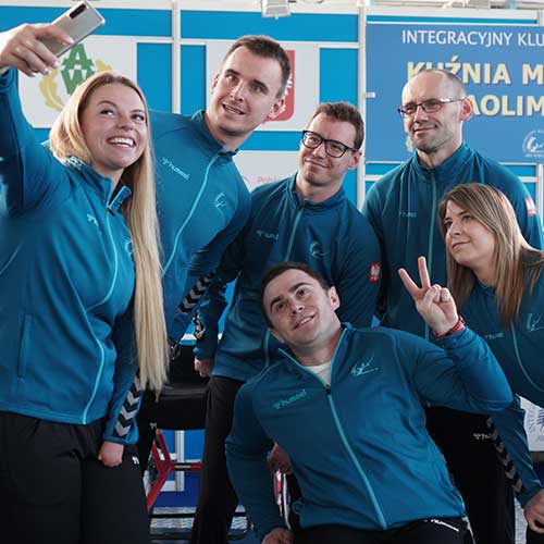 Obraz przedstawiający uśmiechniętych zawodników IKS-AWF w klubowych niebieskich dresach pozujących do wspólnego zdjęcia typu selfie